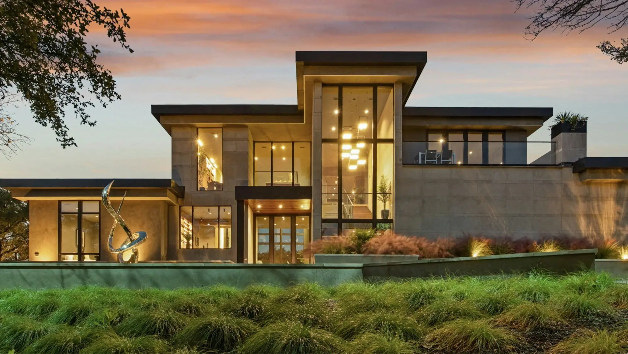 Large modern home with deep flat roofs and glowing windows at dusk