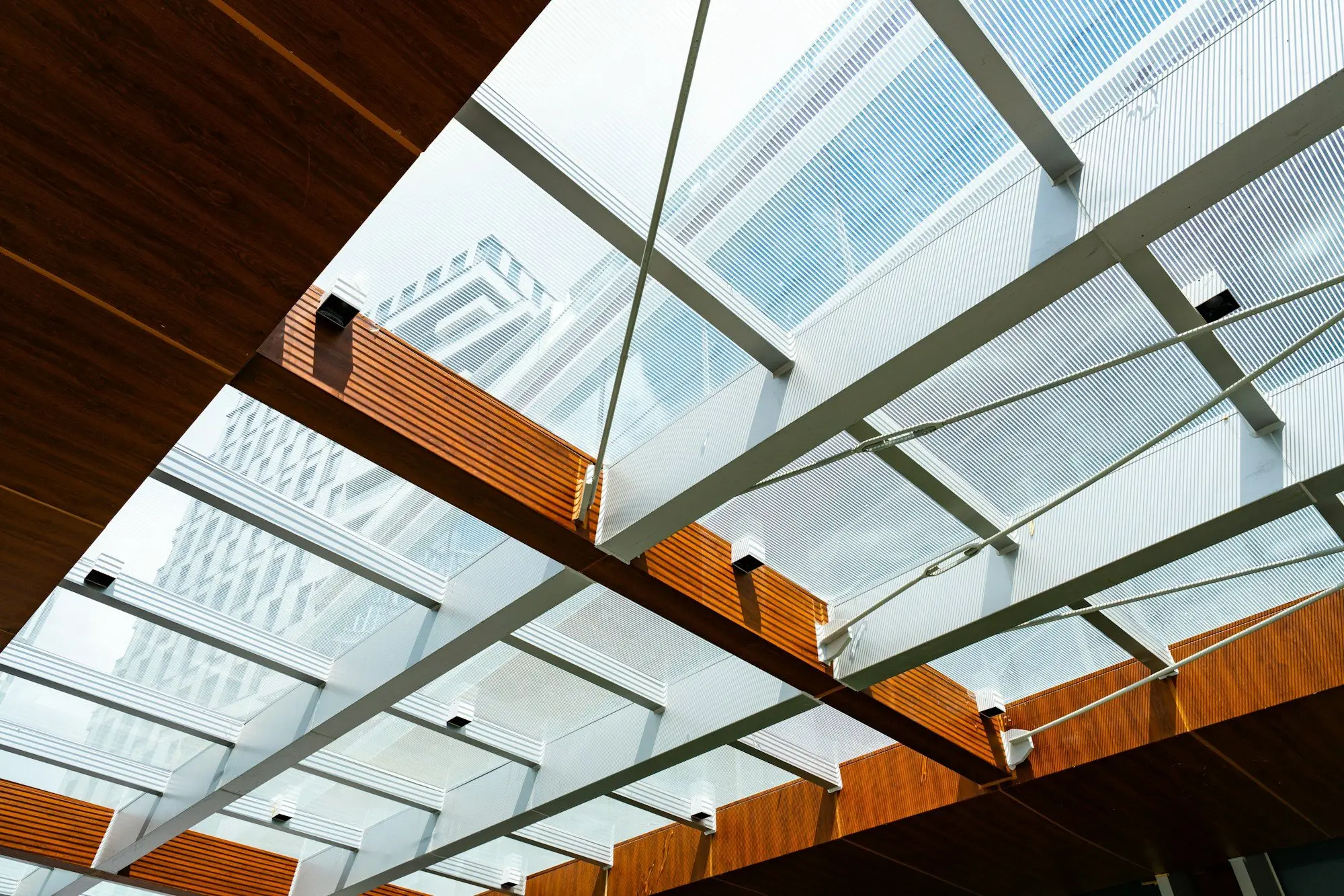Glass roof on a steel frame with warm timber beams, seen from below