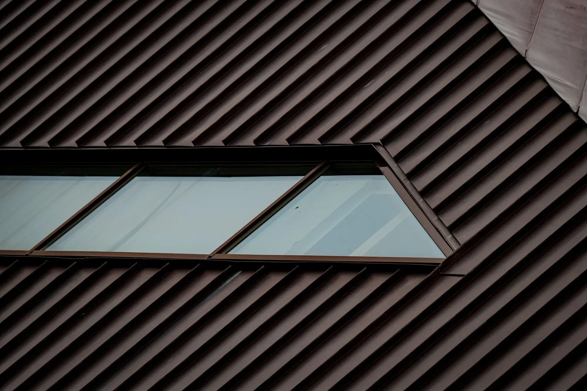 Brown profiled metal roof sheets with a row of flush skylight windows