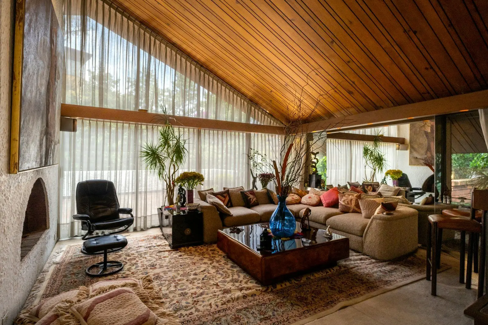 Living room under a vaulted wood panel ceiling with tall windows