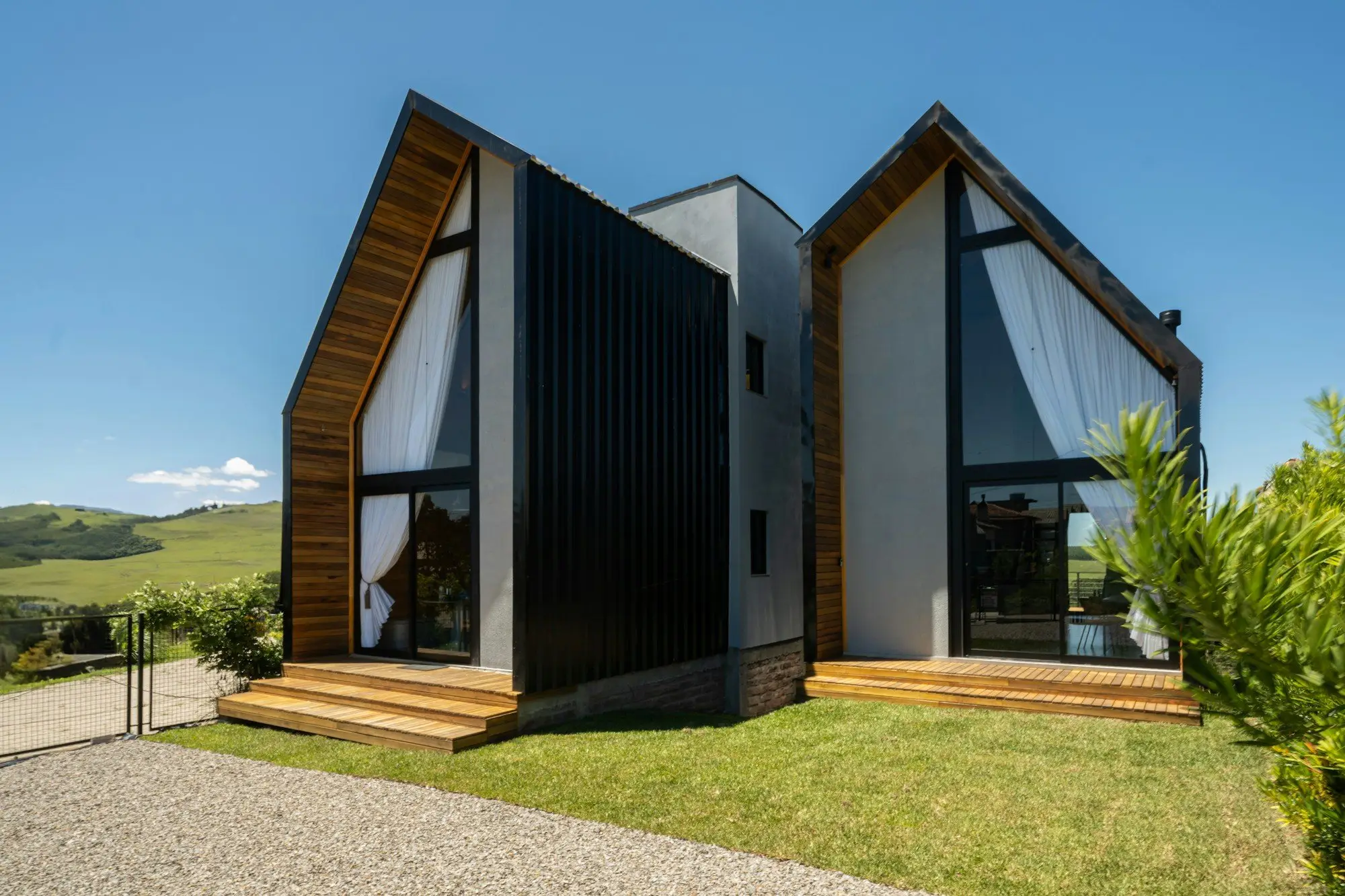 Modern villa with twin A-frame gables, black metal cladding, timber trim and full-height glass